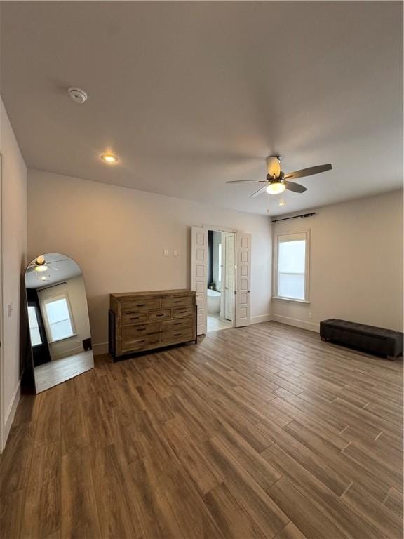 interior space featuring baseboards, ceiling fan, arched walkways, and wood finished floors