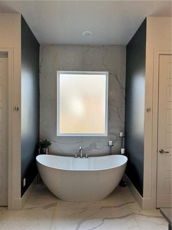 bathroom featuring a freestanding bath and marble finish floor