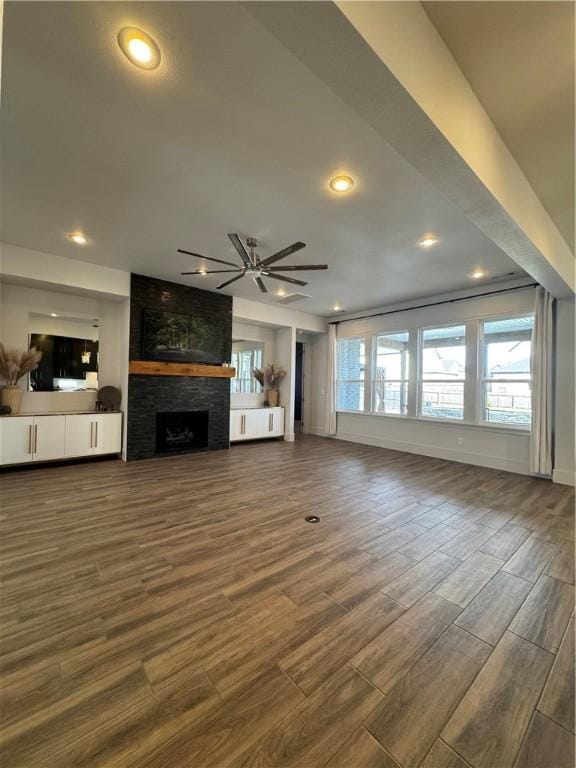 unfurnished living room with a large fireplace, dark wood finished floors, a ceiling fan, and recessed lighting