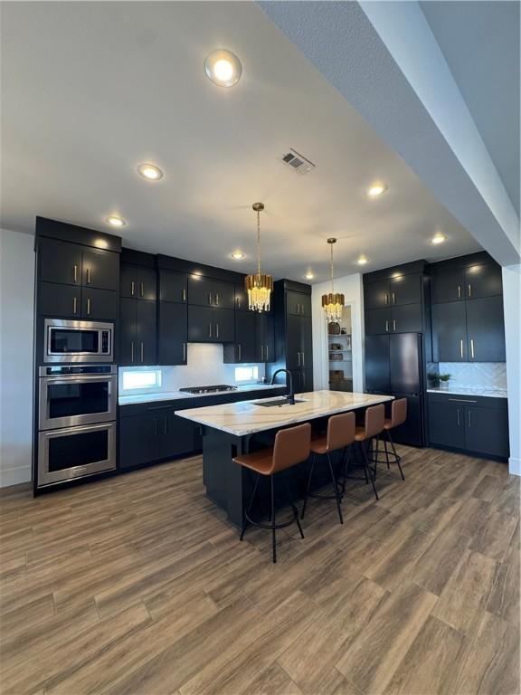 kitchen featuring visible vents, light countertops, dark cabinetry, black appliances, and a sink