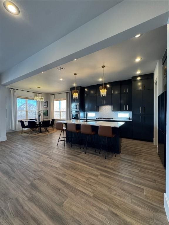 kitchen with a spacious island, a chandelier, light countertops, and dark cabinets