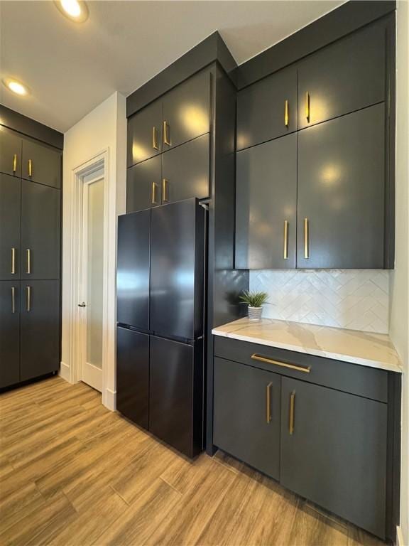 kitchen with light wood-style floors, tasteful backsplash, light countertops, and freestanding refrigerator