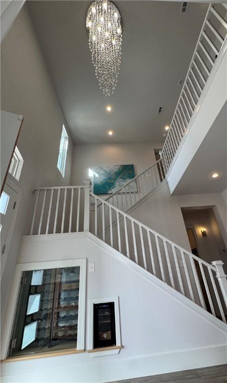 stairway featuring a chandelier, a high ceiling, and recessed lighting