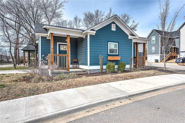 bungalow with covered porch and a shingled roof