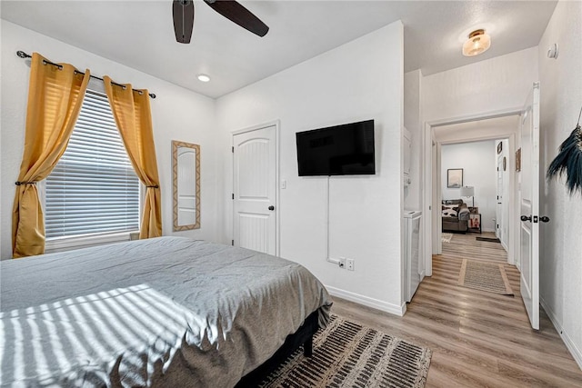 bedroom featuring light wood-style flooring, a ceiling fan, and baseboards