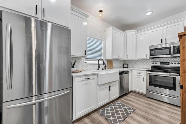 kitchen with light wood-style flooring, a sink, stainless steel appliances, light countertops, and white cabinetry