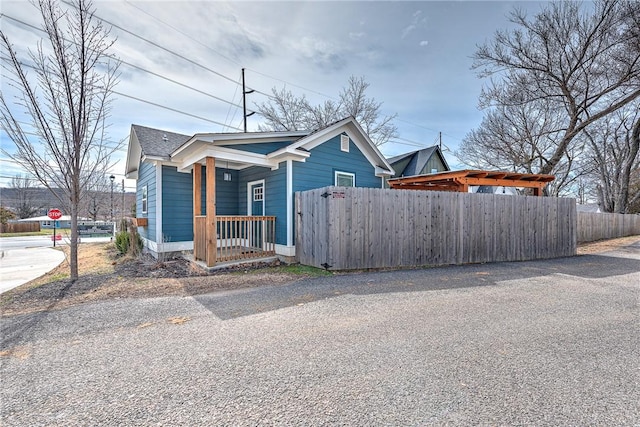 view of front of house with fence, covered porch, and roof with shingles