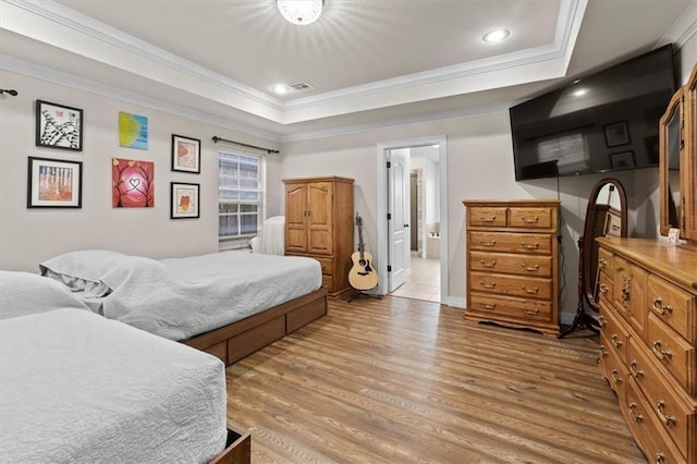 bedroom with a tray ceiling, recessed lighting, light wood-style floors, ornamental molding, and baseboards