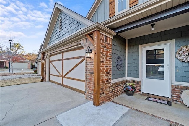 property entrance with a garage, brick siding, board and batten siding, and concrete driveway