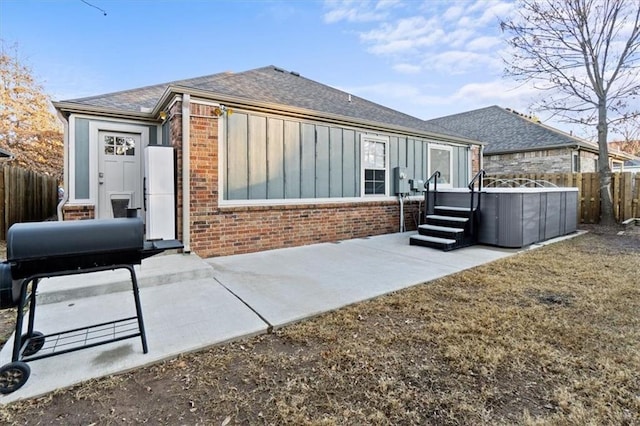 rear view of property with brick siding, fence, roof with shingles, board and batten siding, and a patio area