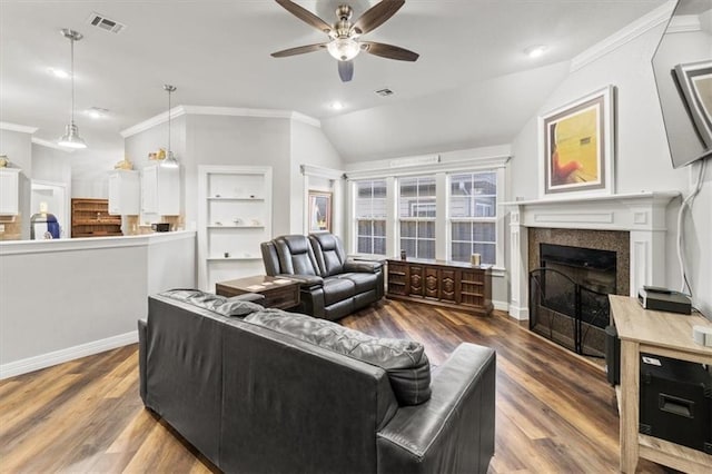 living room with ornamental molding, visible vents, a fireplace, and wood finished floors