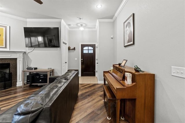 foyer with crown molding, visible vents, dark wood finished floors, and a tiled fireplace