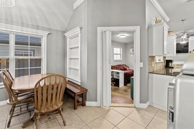 dining area featuring light tile patterned floors, lofted ceiling, and baseboards