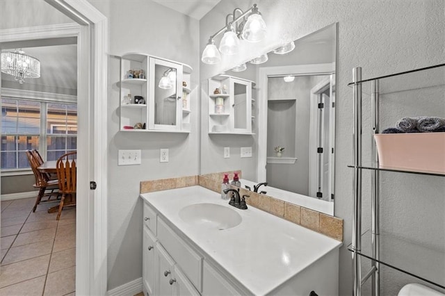 bathroom featuring vanity, baseboards, a notable chandelier, and tile patterned floors