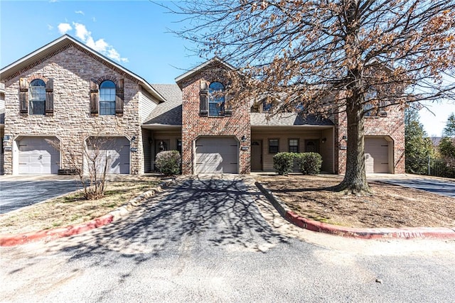 view of front of home with driveway, an attached garage, and brick siding