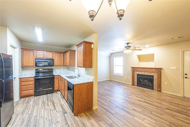 kitchen featuring a fireplace, visible vents, a sink, light wood-type flooring, and black appliances