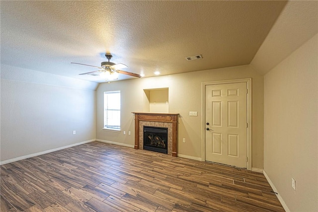 unfurnished living room featuring dark wood-style floors, visible vents, a ceiling fan, a tile fireplace, and baseboards