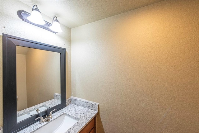 bathroom featuring a textured wall, a textured ceiling, and vanity