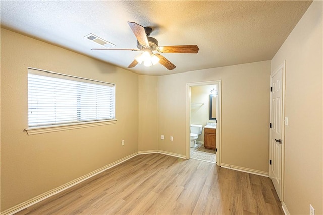 spare room featuring baseboards, visible vents, a ceiling fan, a textured ceiling, and light wood-style floors