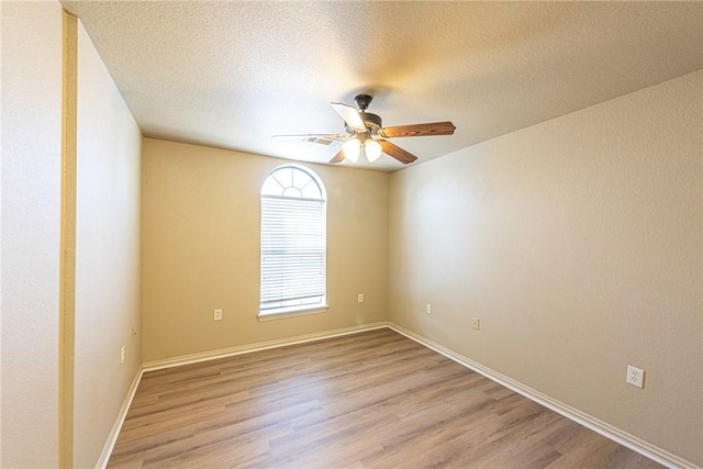 spare room with visible vents, a textured ceiling, light wood-style flooring, and a ceiling fan