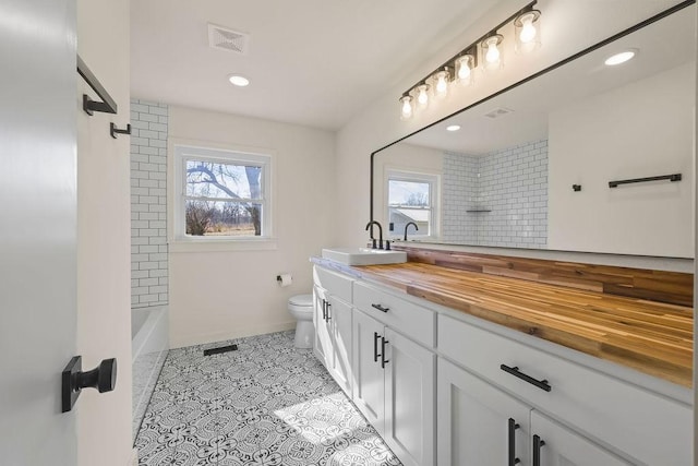 full bathroom featuring toilet, a wealth of natural light, vanity, and visible vents