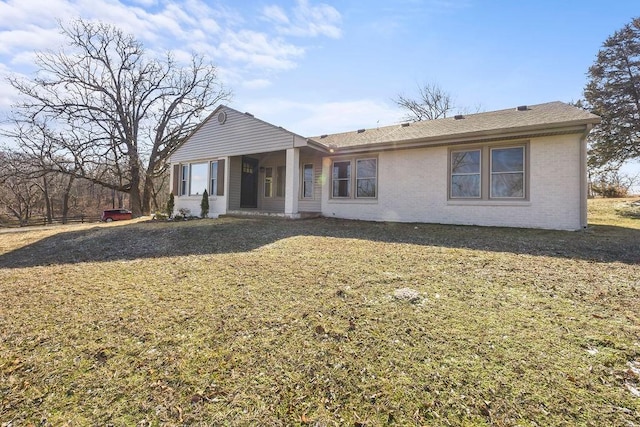 rear view of house with brick siding and a lawn