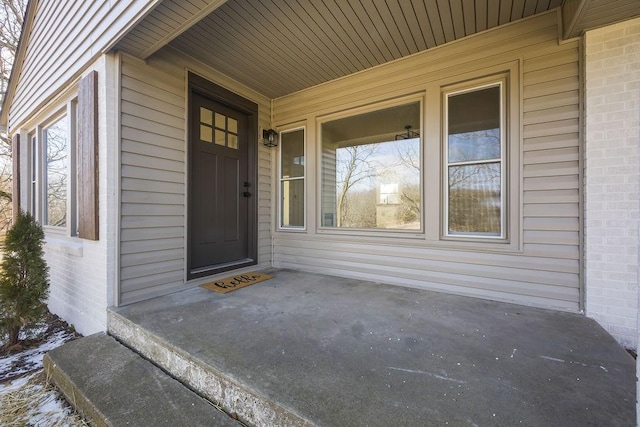 entrance to property with covered porch and brick siding