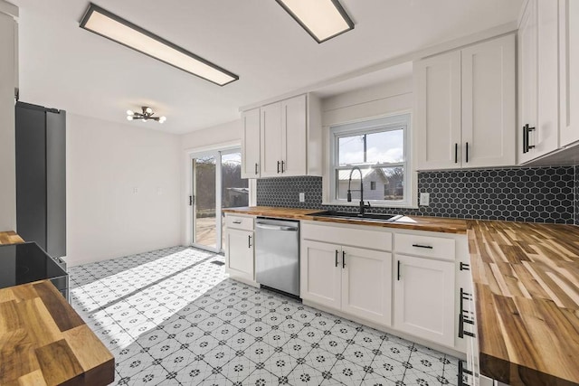 kitchen featuring butcher block countertops, white cabinetry, dishwasher, and a sink