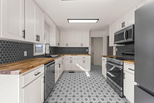 kitchen with appliances with stainless steel finishes, white cabinets, wooden counters, and a sink