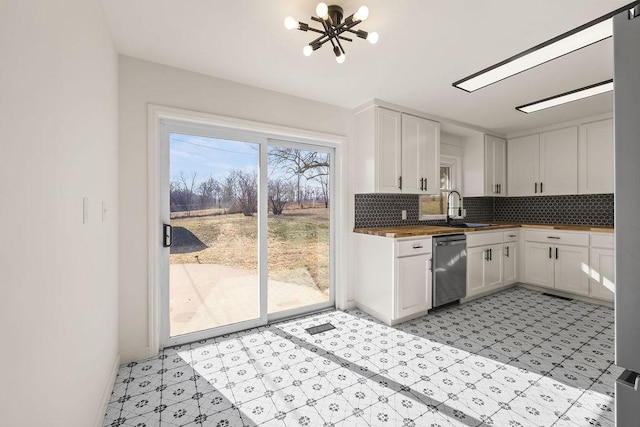 kitchen featuring stainless steel dishwasher, a sink, white cabinetry, and tasteful backsplash