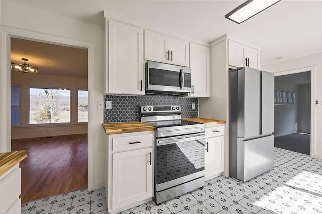 kitchen with appliances with stainless steel finishes, white cabinets, and wood counters