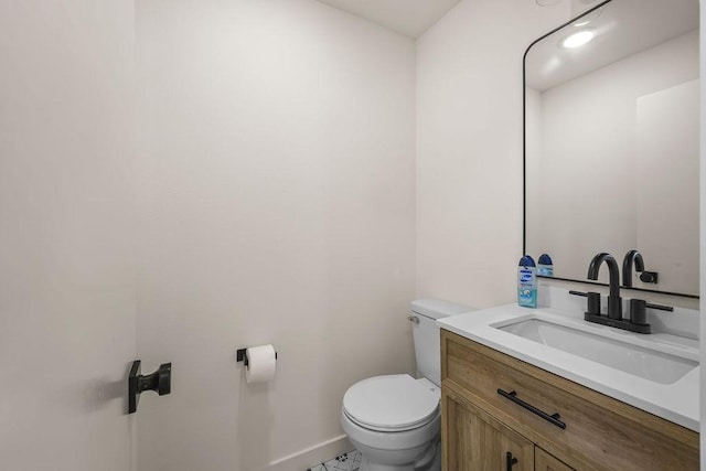 half bathroom featuring baseboards, vanity, and toilet