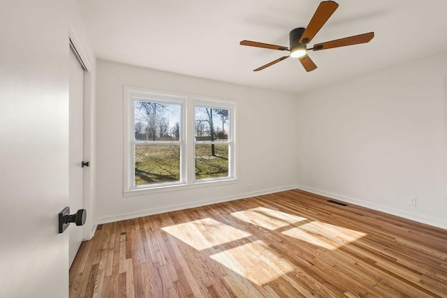 empty room with baseboards, visible vents, ceiling fan, and wood finished floors