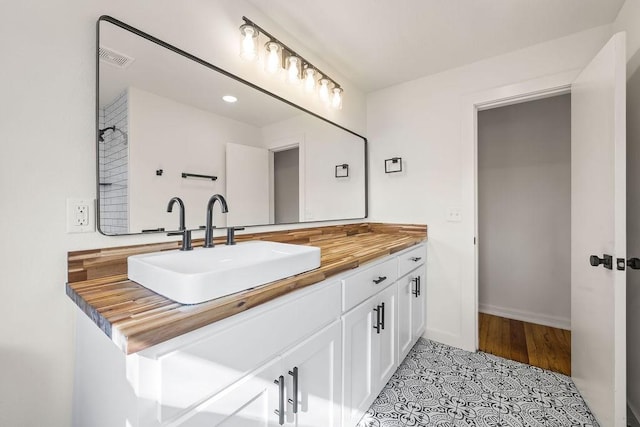 bathroom featuring baseboards, visible vents, tile patterned flooring, and vanity