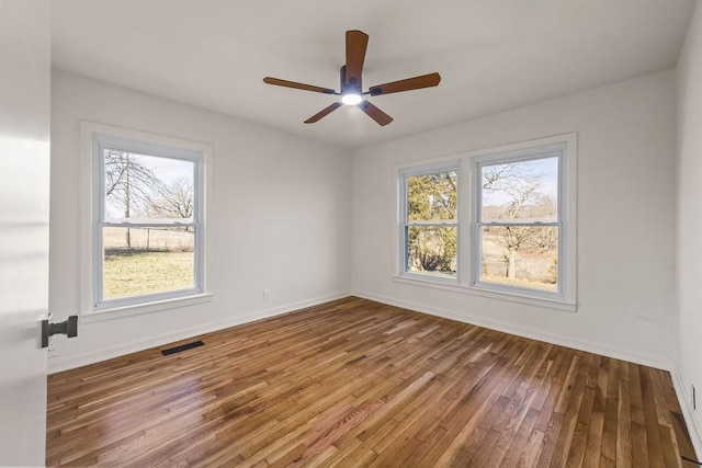 spare room with baseboards, visible vents, ceiling fan, and wood finished floors