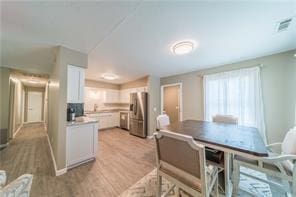 dining area featuring a wealth of natural light, baseboards, visible vents, and light wood finished floors