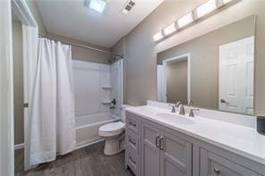 full bathroom featuring toilet, wood finished floors, shower / tub combo with curtain, and vanity