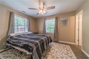 bedroom with a ceiling fan, multiple windows, baseboards, and wood finished floors