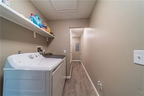 washroom featuring wood finished floors, washer and dryer, laundry area, electric panel, and baseboards