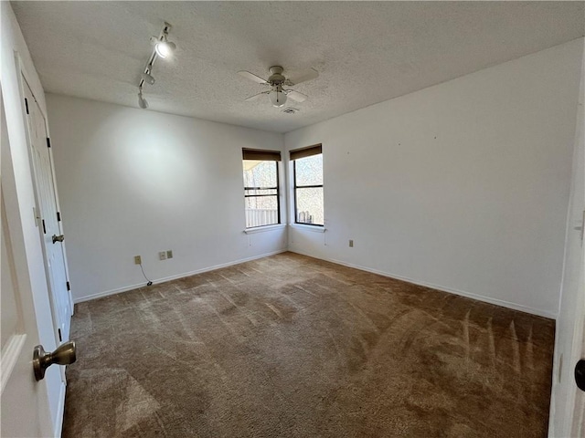 carpeted spare room with a ceiling fan, baseboards, a textured ceiling, and track lighting