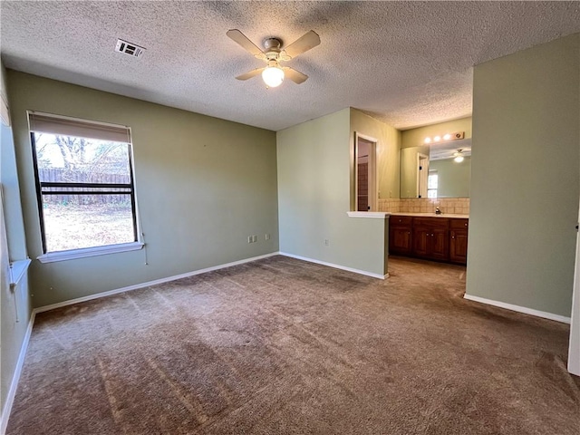 unfurnished bedroom featuring connected bathroom, a sink, carpet flooring, visible vents, and baseboards