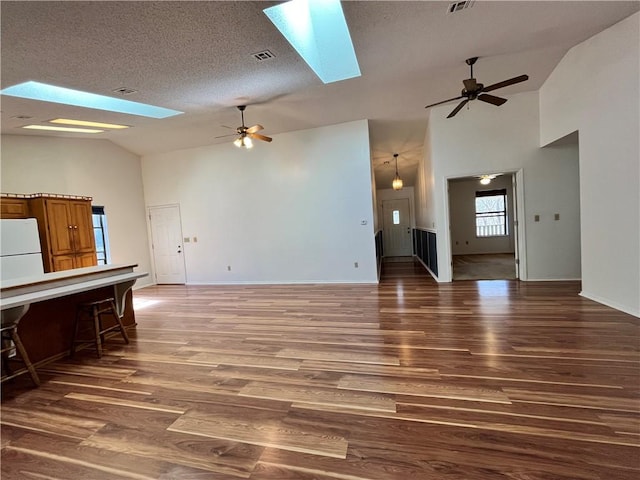 living area featuring a skylight, a textured ceiling, visible vents, and wood finished floors