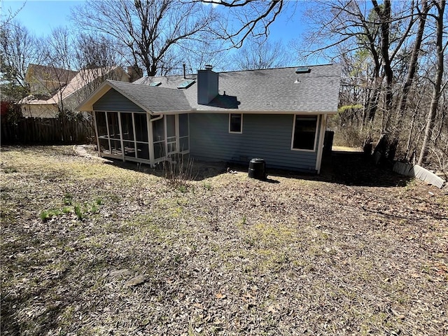 rear view of house featuring a sunroom, roof with shingles, fence, and a chimney