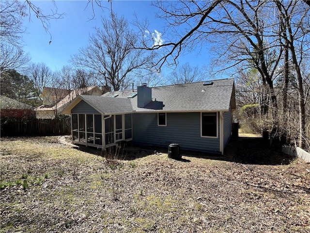 rear view of property featuring a shingled roof, a chimney, fence, and a sunroom