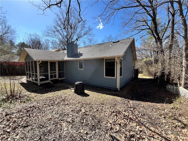 rear view of property with a sunroom, a shingled roof, a chimney, and fence