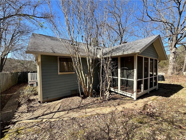 back of house with a sunroom, a shingled roof, and fence