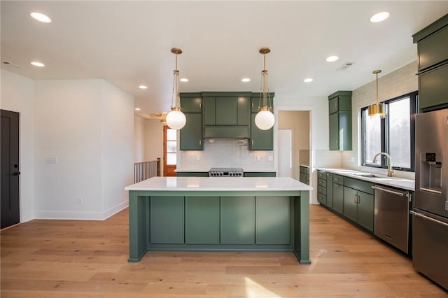 kitchen featuring appliances with stainless steel finishes, light countertops, green cabinets, and light wood-style floors