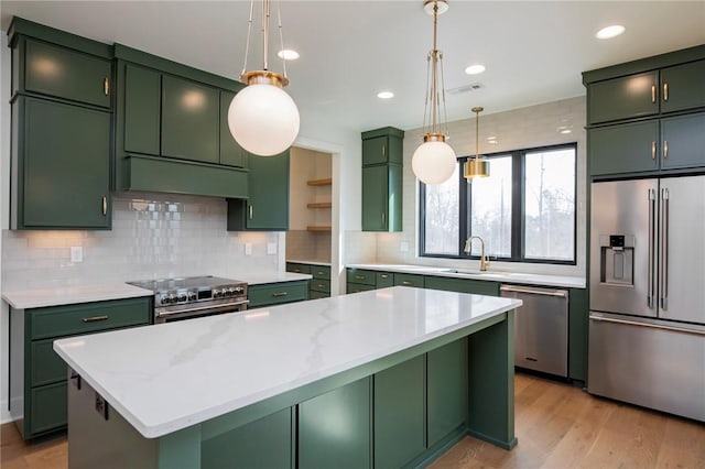 kitchen with a sink, premium appliances, green cabinets, and range hood