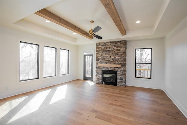 unfurnished living room featuring light wood finished floors, a fireplace, baseboards, and a tray ceiling