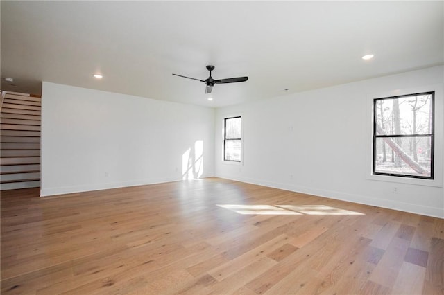 empty room with stairs, recessed lighting, light wood-style floors, and baseboards